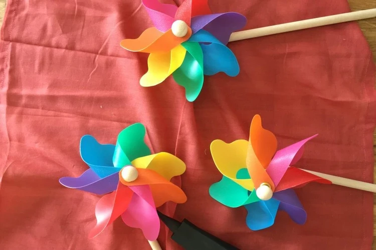 Mehrere bunte Windr&auml;dchen liegen auf einem roten Stoff.