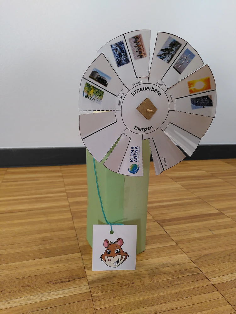 Ein Selbstbegasteltes Energierad zeigt verschiedene Formen erneuerbarer Energie wie Sonne, Wasser und Wind.